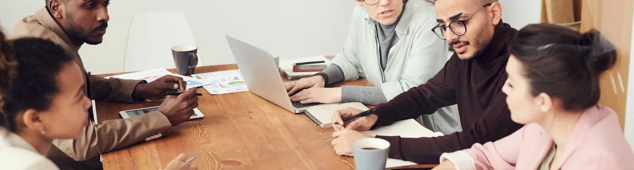 Team working together around a table with laptops